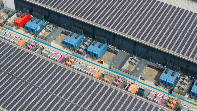 Aerial view of a data center facility featuring rows of solar panels on the roof and industrial HVAC server cooling units in Hemel Hempstead, England, United Kingdom.