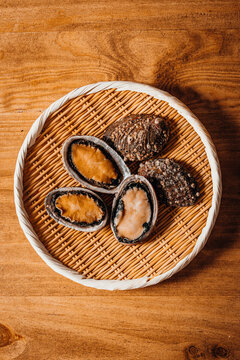 Raw fresh abalone displayed in a traditional woven bamboo basket