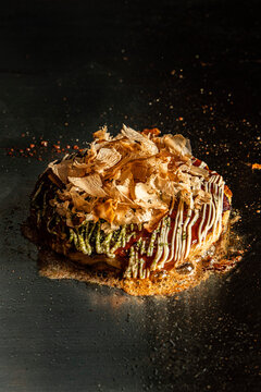 Japanese okonomiyaki pancake topped with sauce and bonito flakes