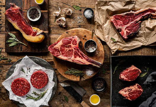 Overhead view of various raw beef cuts, steaks, and burger patties
