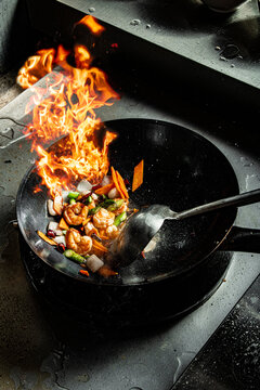 Stir-frying prawns and vegetables in a flaming wok