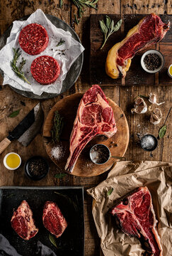 Overhead view of various raw beef cuts, steaks, and burger patties