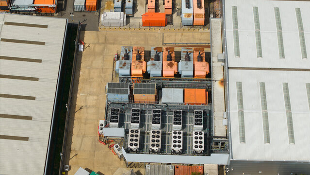 Aerial view of a data center facility featuring rows of industrial external cooling units and HVAC systems on a concrete rooftop in Hemel Hempstead, England, United Kingdom.