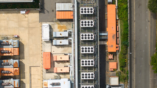 Aerial view of a data center featuring rows of external cooling units and industrial infrastructure with orange containers in Hemel Hempstead, England, United Kingdom.