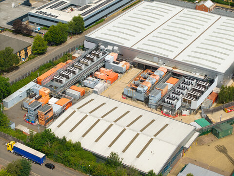 Aerial view of a data center with rows of external cooling units for AI technology, next to an industrial warehouse with a truck on the road in Hemel Hempstead, England, United Kingdom.