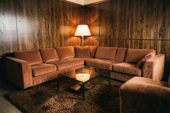 Retro 1970s lounge with burnt orange velvet sofa and teak paneling