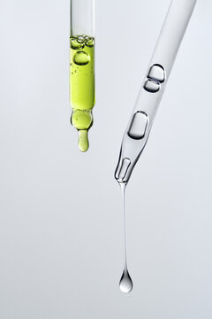 Glass pipettes with different liquids on gray backdrop with copy space