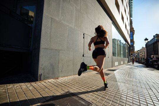 Runner moves fast along city sidewalk in afternoon light