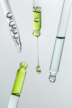 Glass pipettes with different liquids on gray backdrop with copy space