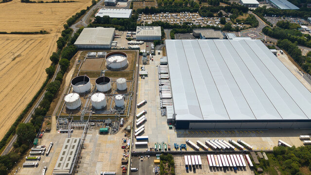 Aerial view of the Buncefield Oil Depot and distribution centre with large storage tanks and a warehouse facility featuring rows of HGVs in Hemel Hempstead, England, United Kingdom.
