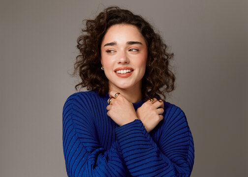 Woman Smiles and Poses With Curly Hair and Blue Sweater
