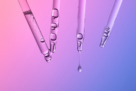 Glass pipettes with liquid on gradient pink and purple background.