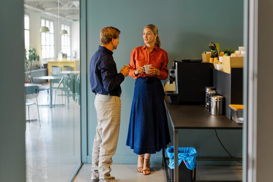 Woman and man doing coffee break in modern office kitchen