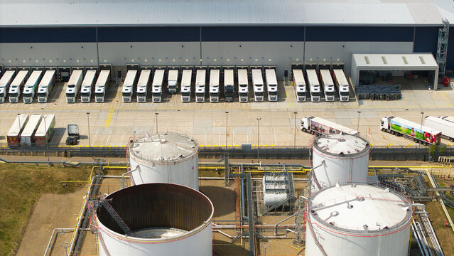Aerial view of the Buncefield Oil Depot and distribution centre featuring large storage tanks and rows of parked HGVs at loading bays, Hemel Hempstead, England, United Kingdom.