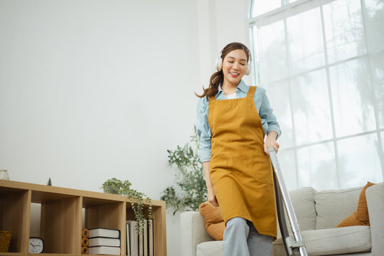 lifestyle healthy living with music headphones; a woman vacuuming at home with. lifestyle guides buyer choices, healthy frames the scene, and living adds useful meaning. In a clear visual scene.