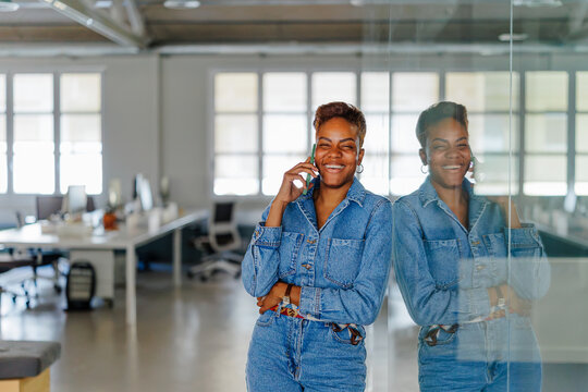 Woman with short smiling and talking on smartphone in modern office