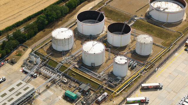 Aerial view of a petroleum oil terminal with large white storage tanks, industrial piping, and tanker trucks in Hemel Hempstead, England, United Kingdom.