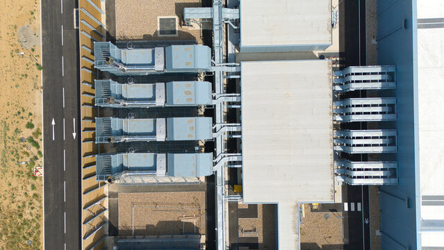 Aerial view of a hyperscale data center rooftop featuring rows of industrial air handling units and chillers connected by metallic ductwork in Hereford, England, United Kingdom.