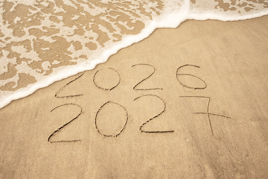 Inscription 2026 and 2027 numbers written on sand.  New Year 2026 replace 2027. Concept on the sea beach