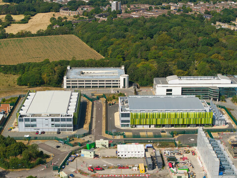Aerial view of a modern data center facility featuring containerised diesel generators and cooling infrastructure for AI operations in Harlow, England, United Kingdom.
