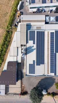 Aerial view of a paint manufacturing facility featuring extensive rooftop solar panels, industrial infrastructure, and storage tanks in Milan, Lombardy, Italy.