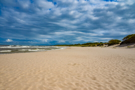 Sand dunes landscape at the sea coastline under cloud sky
