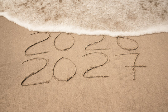 Inscription 2026 and 2027 numbers written on sand.  New Year 2026 replace 2027. Concept on the sea beach