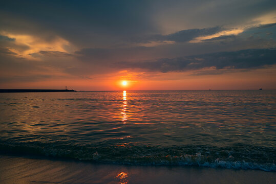 Beautiful colorful sunset in cloud sky at waving sea