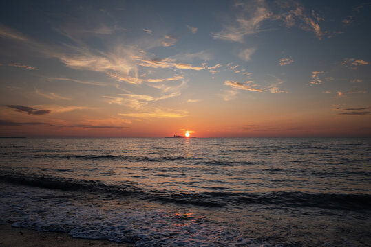 Beautiful colorful sunset in cloud sky at waving sea