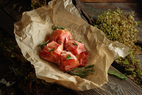 Prosciutto slices with rosemary wrapped in paper.