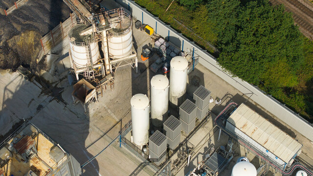 Aerial view of cryogenic storage tanks and gas vaporization systems at a glass manufacturing facility with industrial infrastructure and storage silos in Harlow, England, United Kingdom.