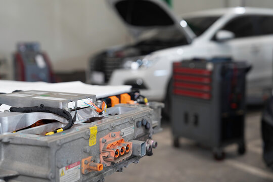 Electric vehicle car services. EV, Technician or Mechanic preparing checks, maintenance, High-voltage battery checks, diagnostic software updates. Diagnosing 12V auxiliary batteries, charging ports