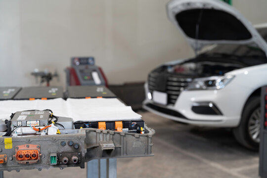 Electric vehicle car services. EV, Technician or Mechanic preparing checks, maintenance, High-voltage battery checks, diagnostic software updates. Diagnosing 12V auxiliary batteries, charging ports