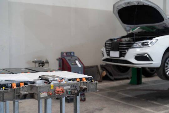 Electric vehicle car services. EV, Technician or Mechanic preparing checks, maintenance, High-voltage battery checks, diagnostic software updates. Diagnosing 12V auxiliary batteries, charging ports