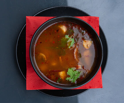 Tom yum thai soup with chicken in black bowl