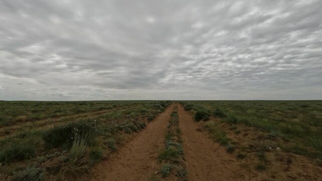 Driving on dirt road through open landscape under cloudy sky