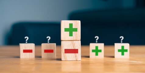 Obraz premium Pros and cons decision making concept with green plus and red minus symbols on wooden blocks