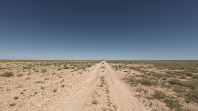 Driving on a dirt road through open landscape under clear blue sky