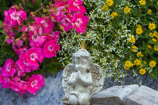 Blumen und Engel Figuren am Grab im Sommer