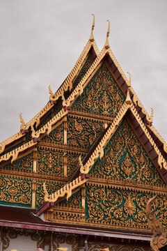 Detailed Thai temple roof gable with ornate gold leaf wood carving patterns.