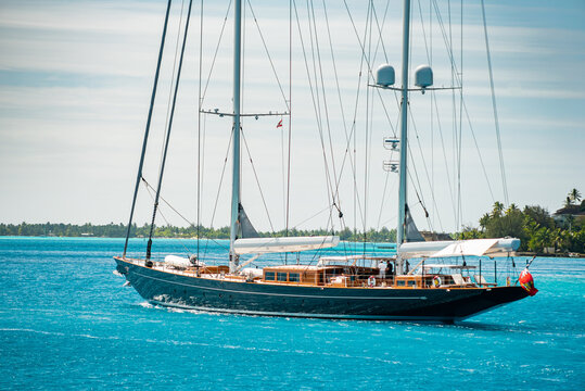 Modern Classic Sailing Superyacht motoring inside the lagoon in Bora Bora, French Polynesia, South Pacific on a sunny day with turquoise waters