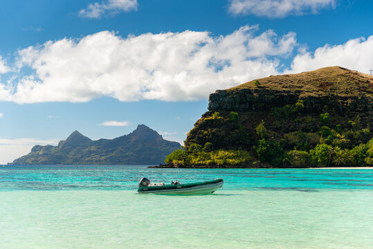 Super yacht tender anchored in tropical paradise beach in Mangareva, French Polynesia, South Pacific, on sunny day with mountains and tropical vegetation