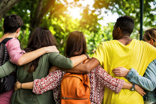 Diverse friends walking together with arms around each other in a park