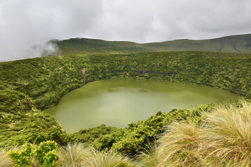 Volcanic crater, Lake Negra surrounded by green vegetation on Flores Island, rain clouds, Azores © Klara Bakalarova