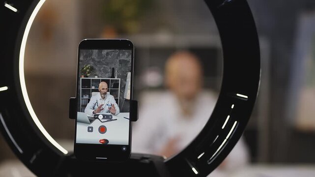 Male cardiologist records video for social media on phone, medical blog concept
