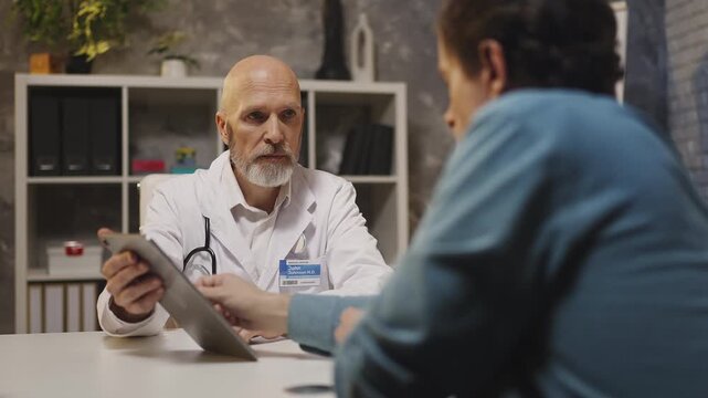 Physician informs patient of serious diagnosis, showing test results on tablet