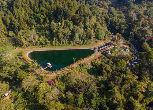 Aerial view of Baturaden reservoir surrounded by lush tropical forest and dense greenery in Baturaden, Central Java, Indonesia.
