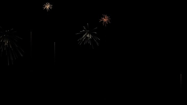 Multiple golden fireworks launching and bursting in the dark night sky backdrop.