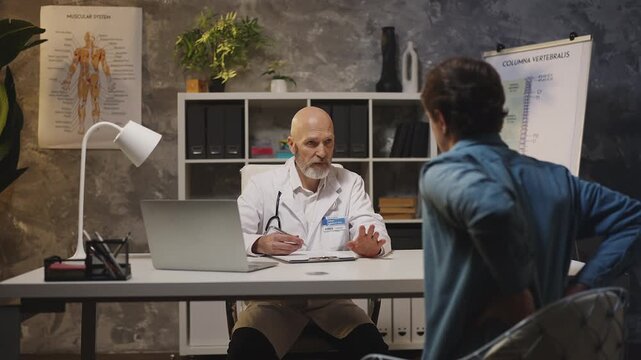 Patient complains about back pain to male doctor during consultation in clinic