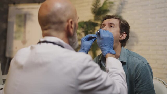 Otolaryngologist examines male patient's throat during hospital consultation